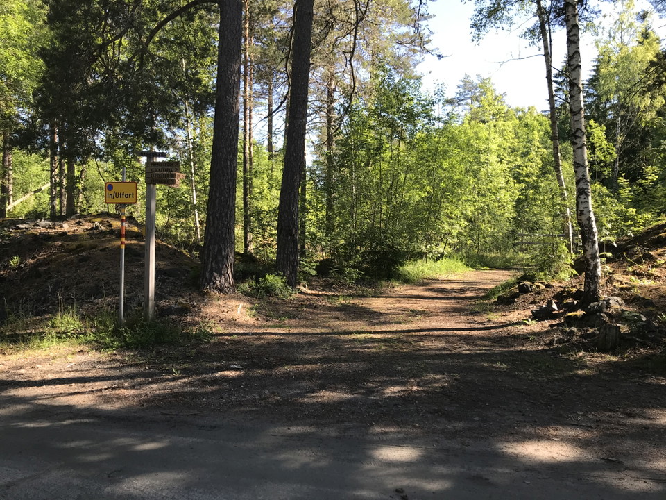 Skogsväg med skylt om att det är in/utfart.