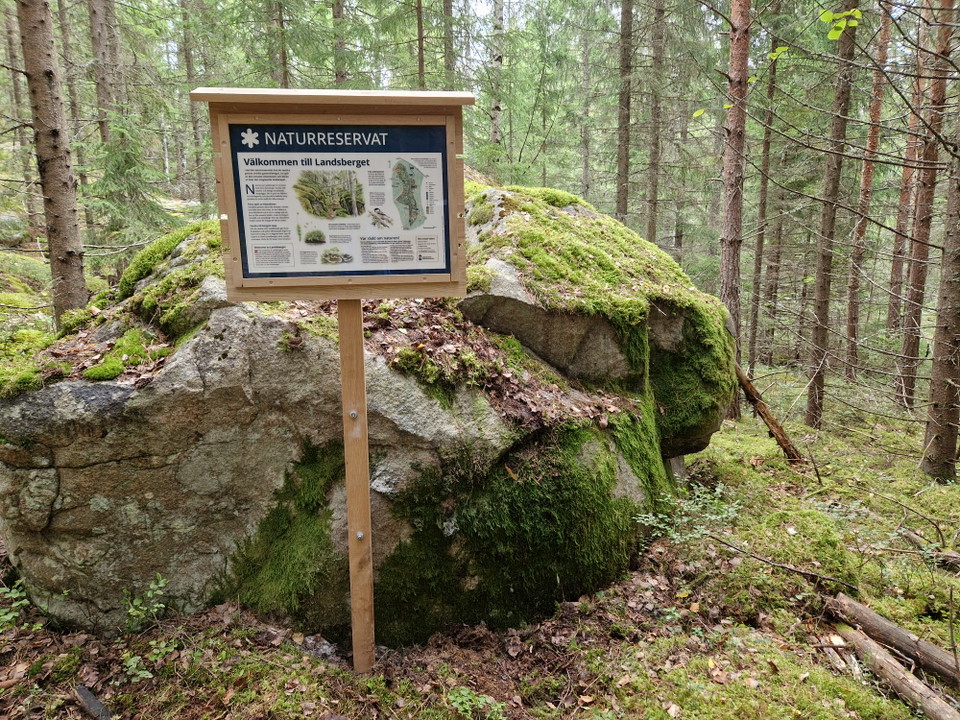 Informationsskylt om naturreservatet står bredvid sten.