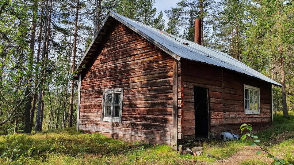 En förfallen timrad stuga.