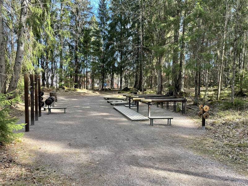 Utegym i trämaterial i skogsmiljö mellan två motionsspår