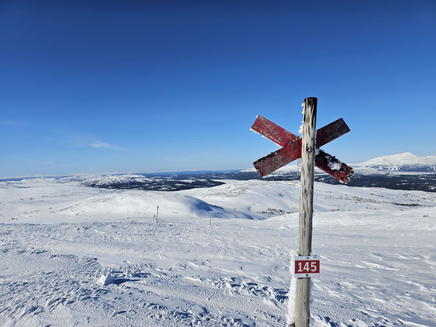 Ledkryss med skylt där det står 145 framför snöiga fjäll