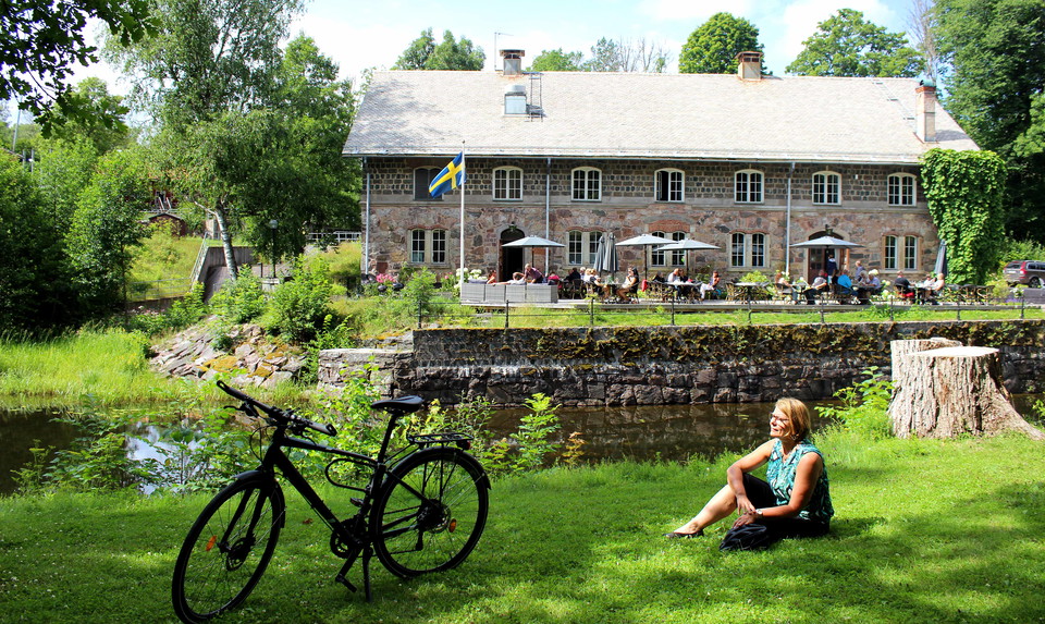 Katarina sitter i gräset bredvid sin cykel vid Kungskvaren i Borgvik