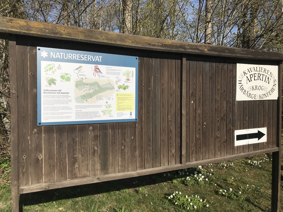 Stor informationstavla i trä som rymmer såväl reservatsskylt som skylt om herrgården.
