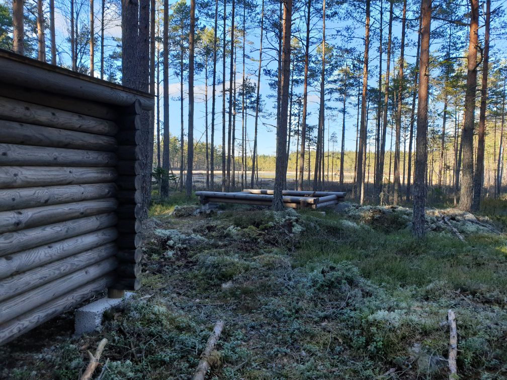 Rastplats med vindskydd och grillplats vid en tjärn.