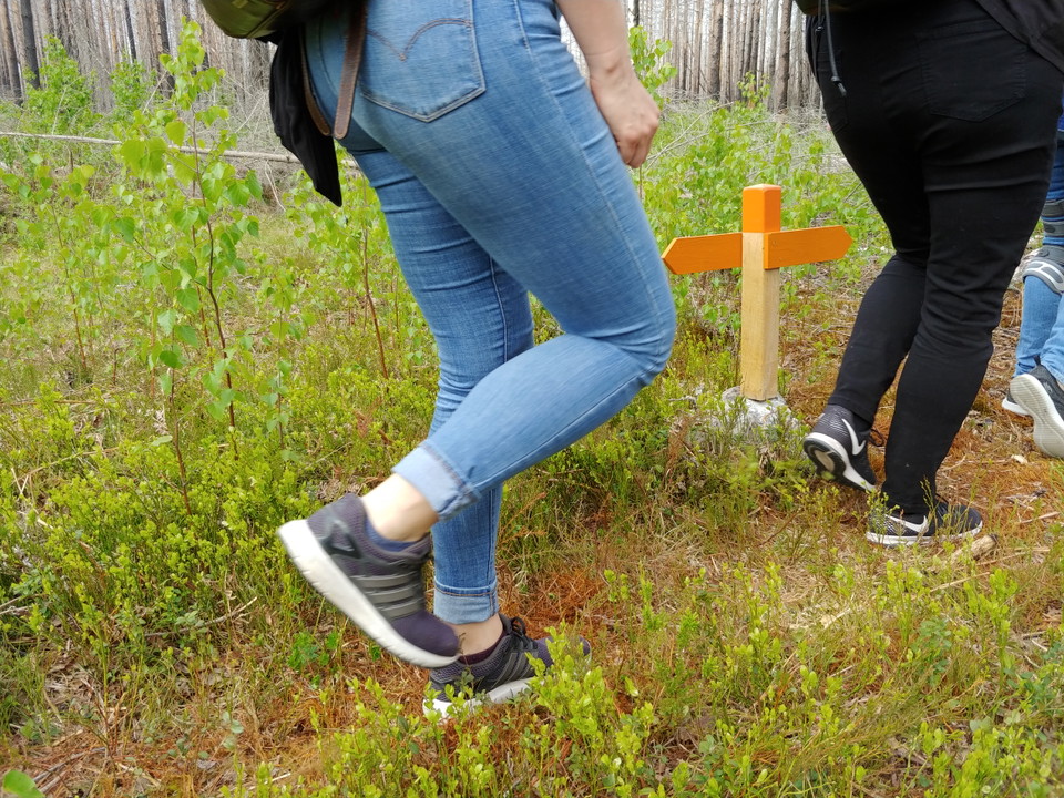 Ben tillhörande två människor som går på en stig. En orange vägvisare syns mellan de båda människorna.