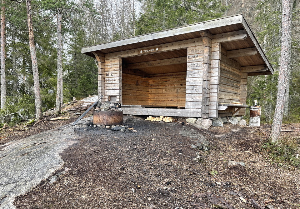 Vindskydd i knuttimmer. En rund grillstad finns utanför.