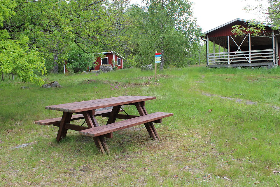 Bild på sittbänk med bord, gräsyta och byggnad/paviljong på Östra holmen.