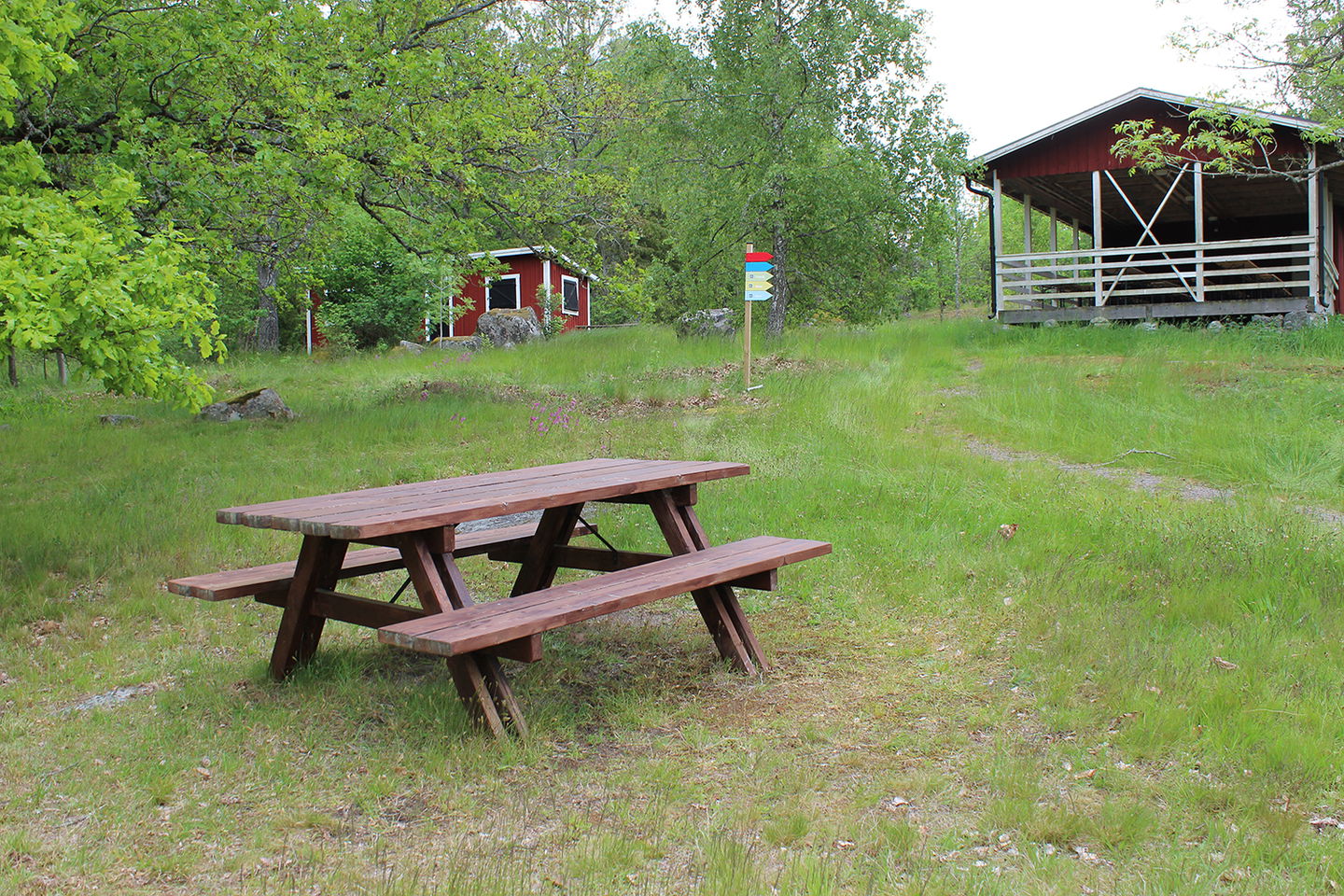 Bild på sittbänk med bord, gräsyta och byggnad/paviljong på Östra holmen.