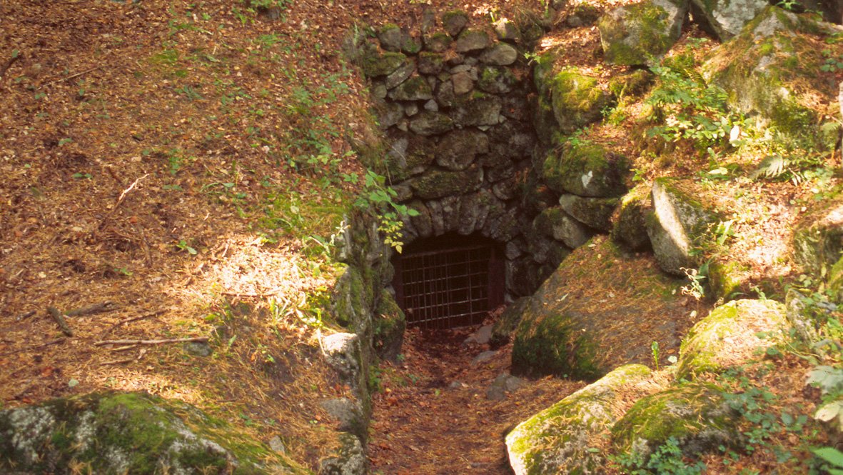 En stenlagd ingång med galler till grottan på Balsberget.
