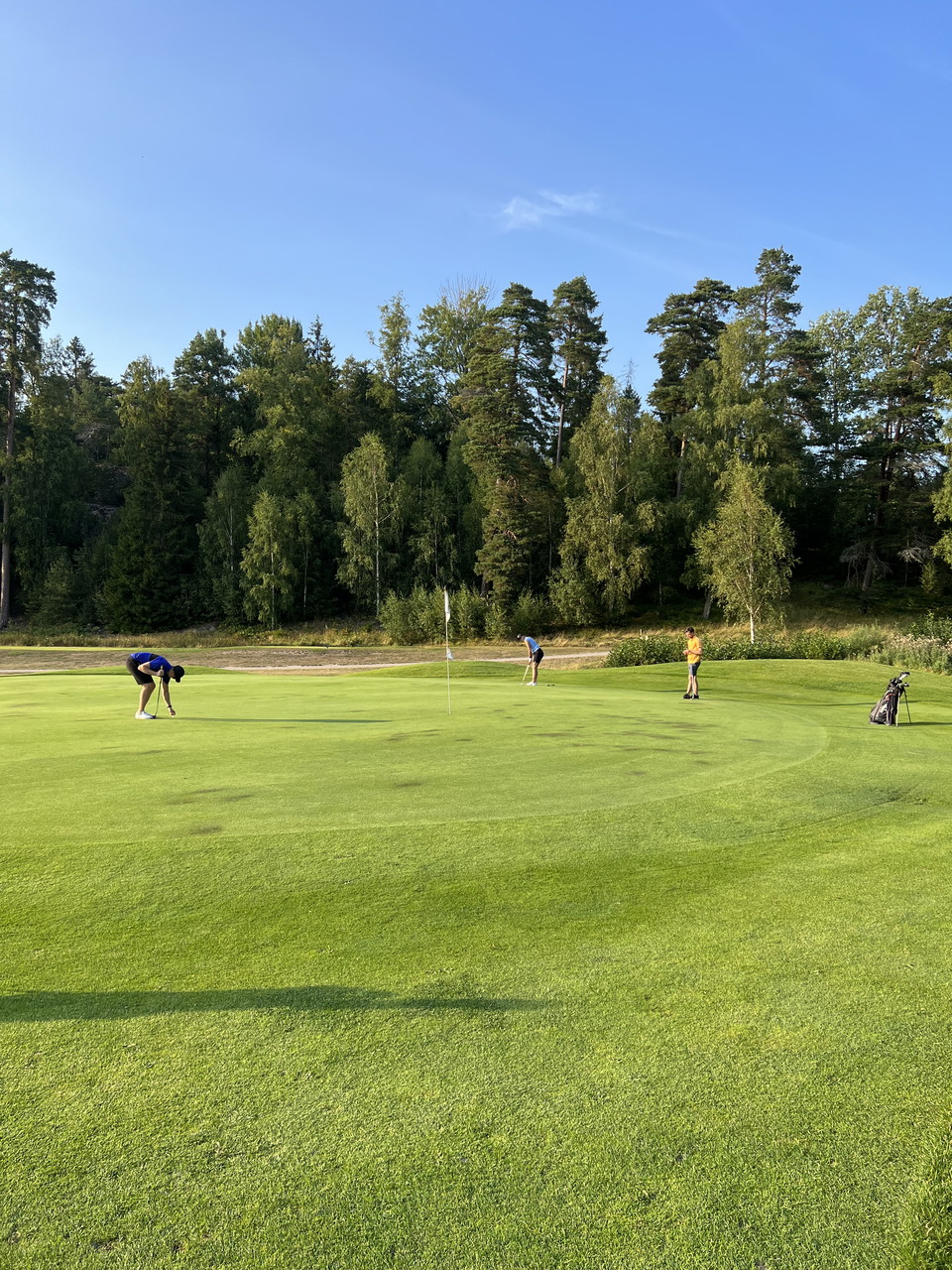 Tre spelare på green på golfbanan