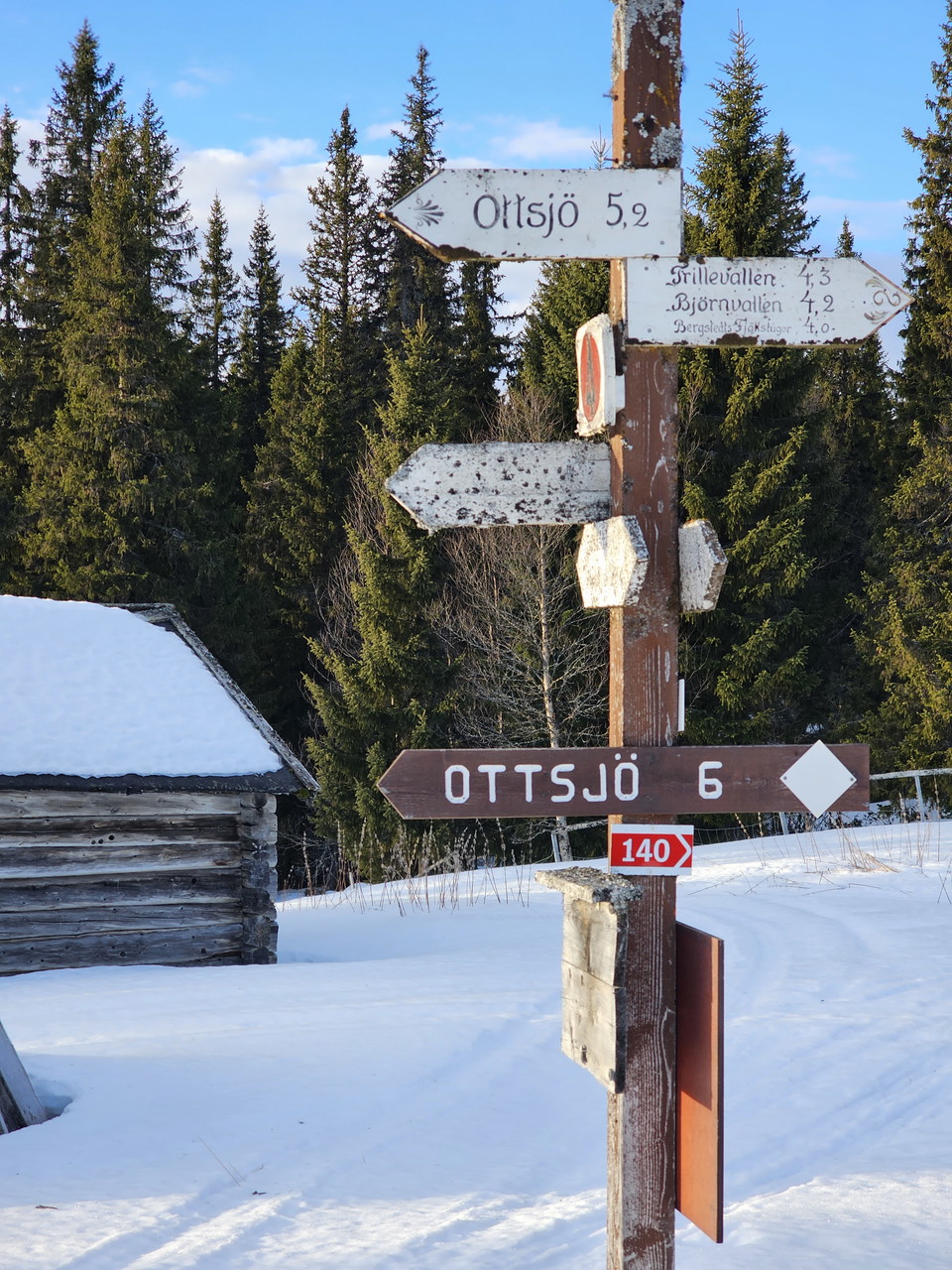 Hänvisningsskyltar i trä uppsatta på en stolpe.