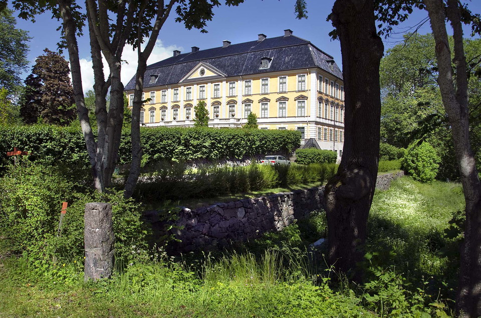 Gult slott med träd i förgrunden.