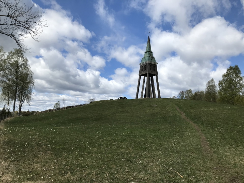 Gräskulle med en klockstapel och rastbord på toppen.