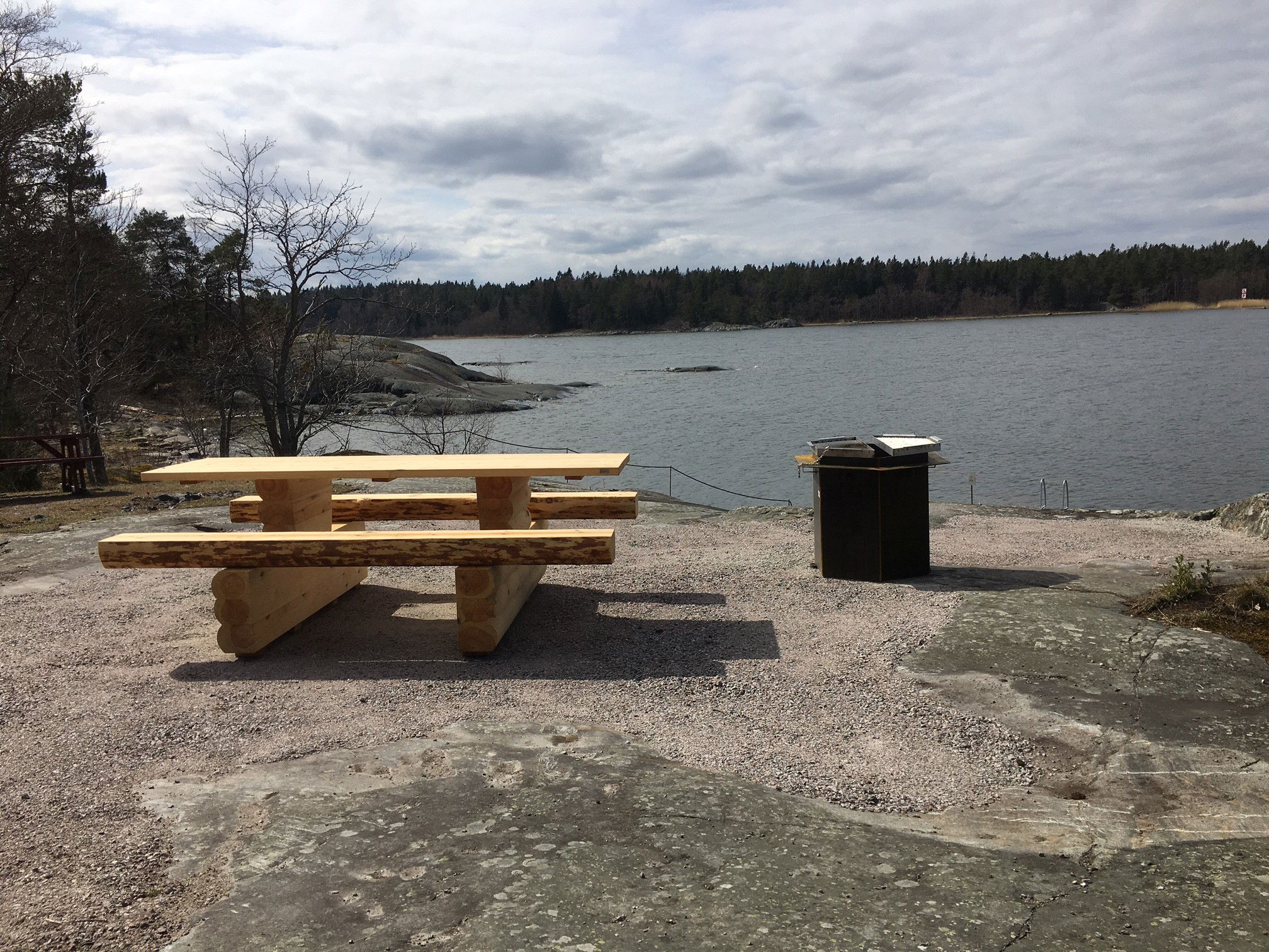Tillgänglighetsanpassat fikabord och en grill med utsikt över vattnet
