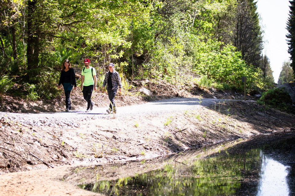 Tre personer vandrar längs med krämbolsleden, de har skogskläder på sig och ser glada ut.
