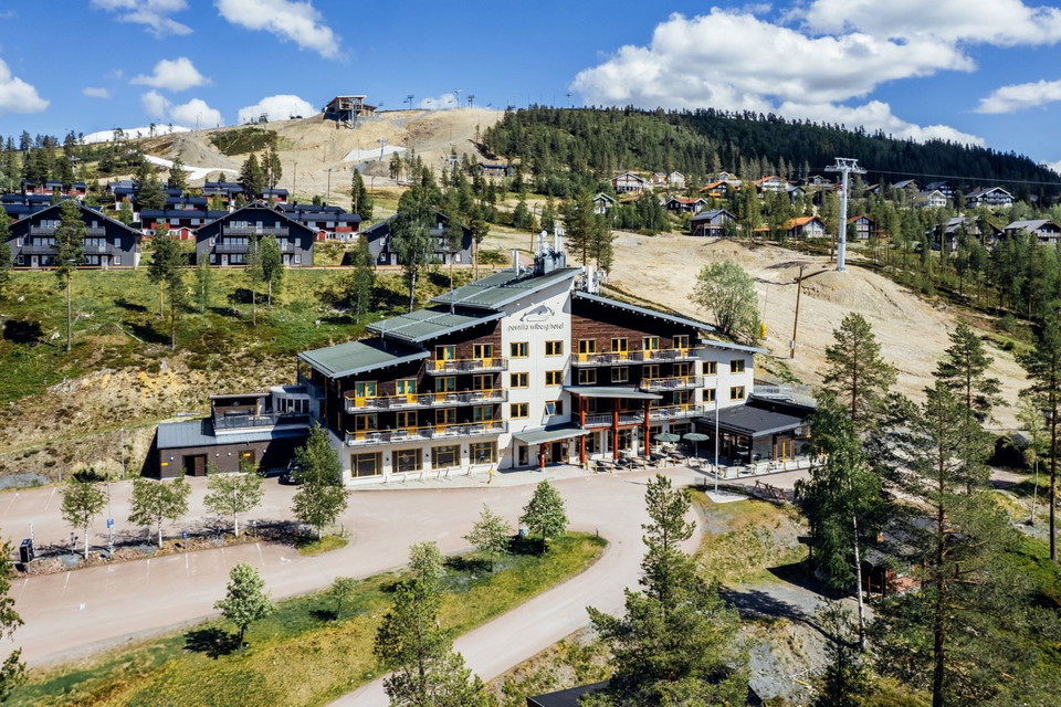 En byggnad med träd och berg i bakgrunden.