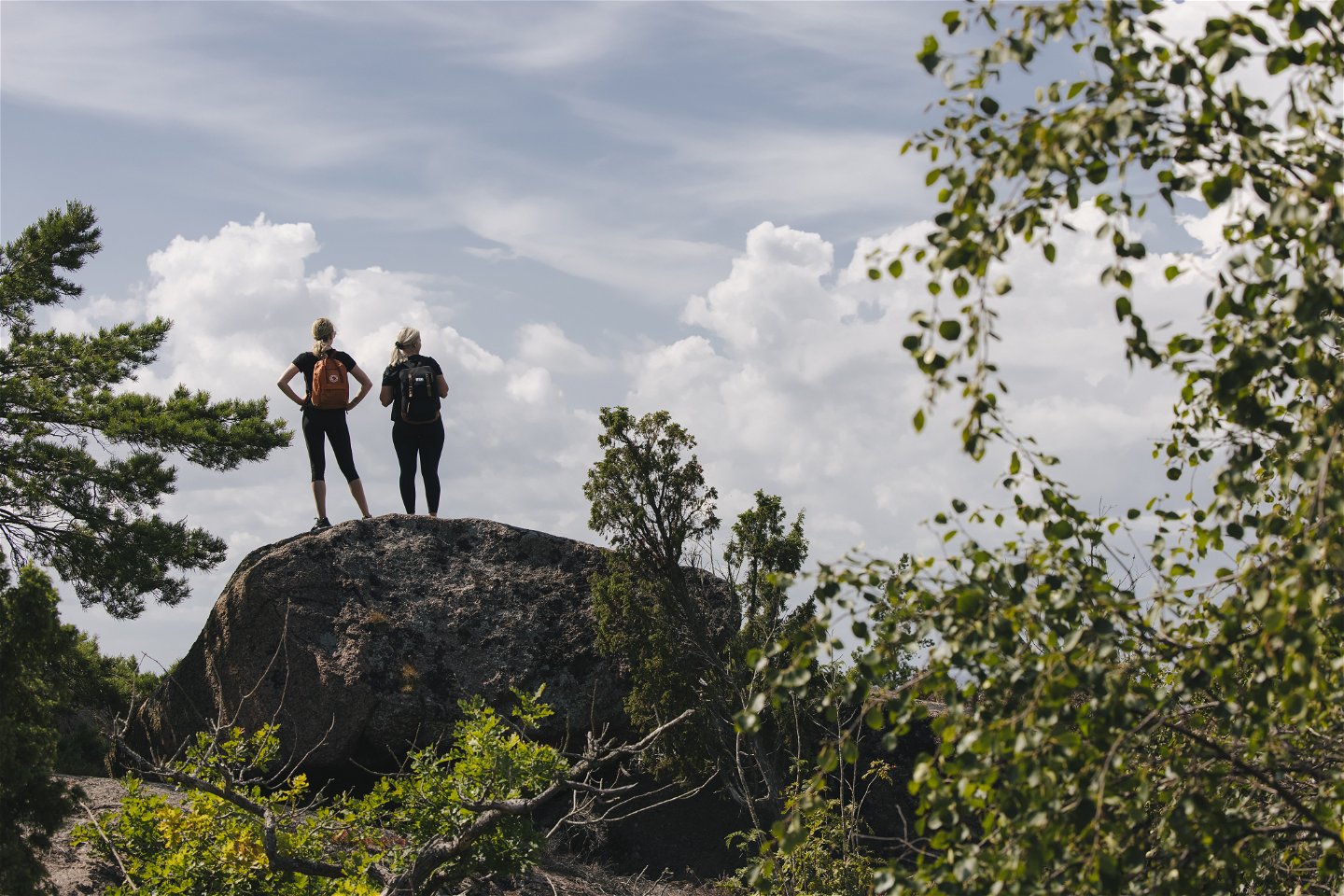 Två personer står på stor sten och tittar på utsikten