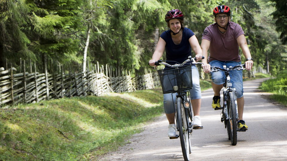 Två cyklister cyklar på en grusväg.