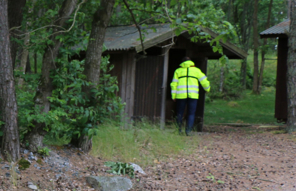 En person i reflexjacka går in på en toalett.