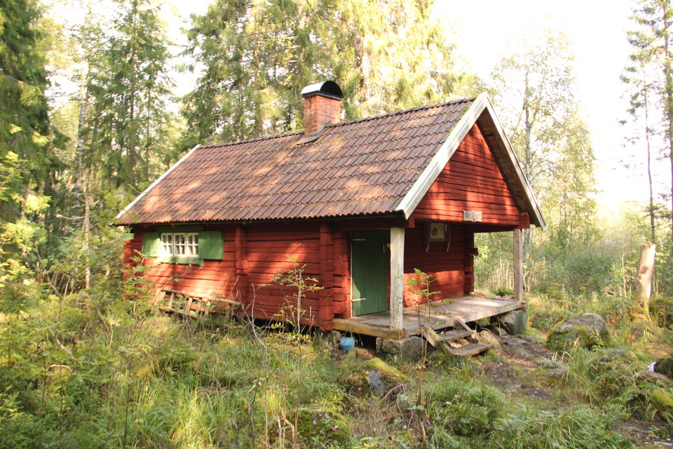 Röd stuga med fönsterluckor.