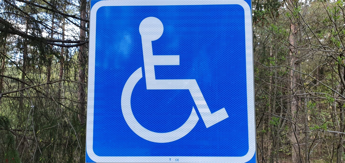 Blå/vit skylt med symbol för handikapparkering.