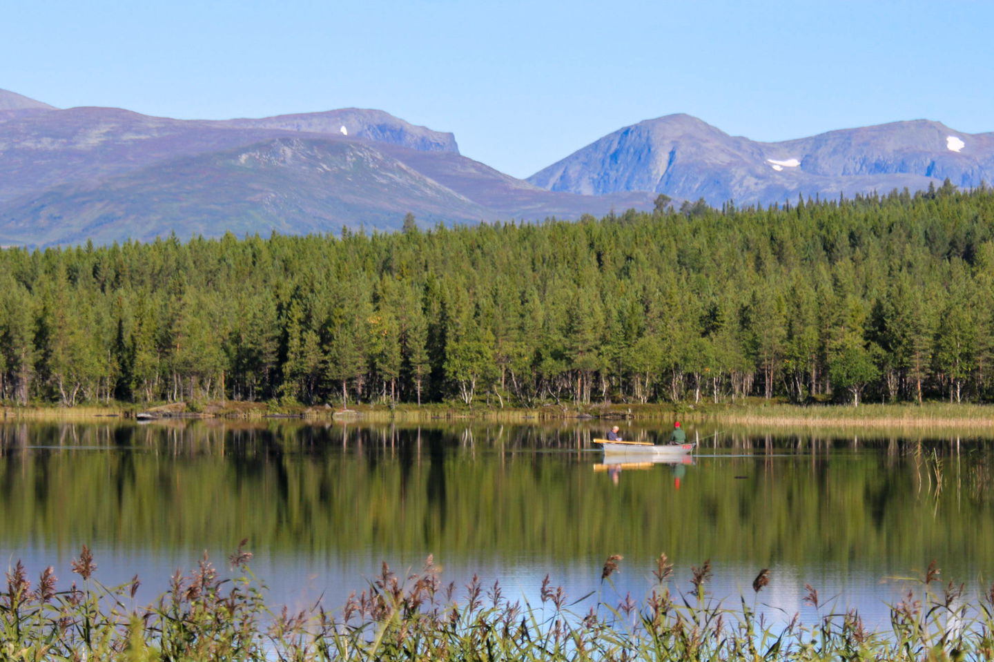 Fiskare i båt på en sjö med fina fjäll i bakgrunden