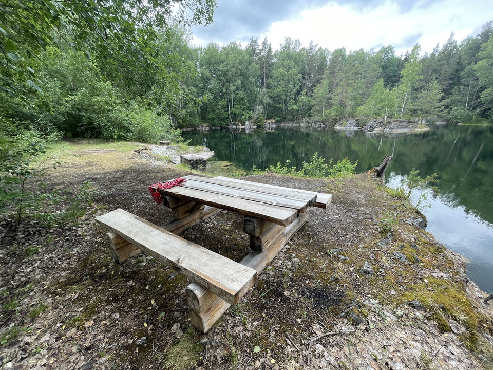 Picknickbord med bänkar och utsikt över ett gammalt stenbrott. På bordet ligger en rod bikini.
