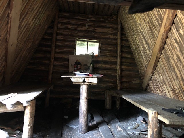 Inne i Kolarkojan. Två enkla britsar längs väggarna och ett bord i mitten.