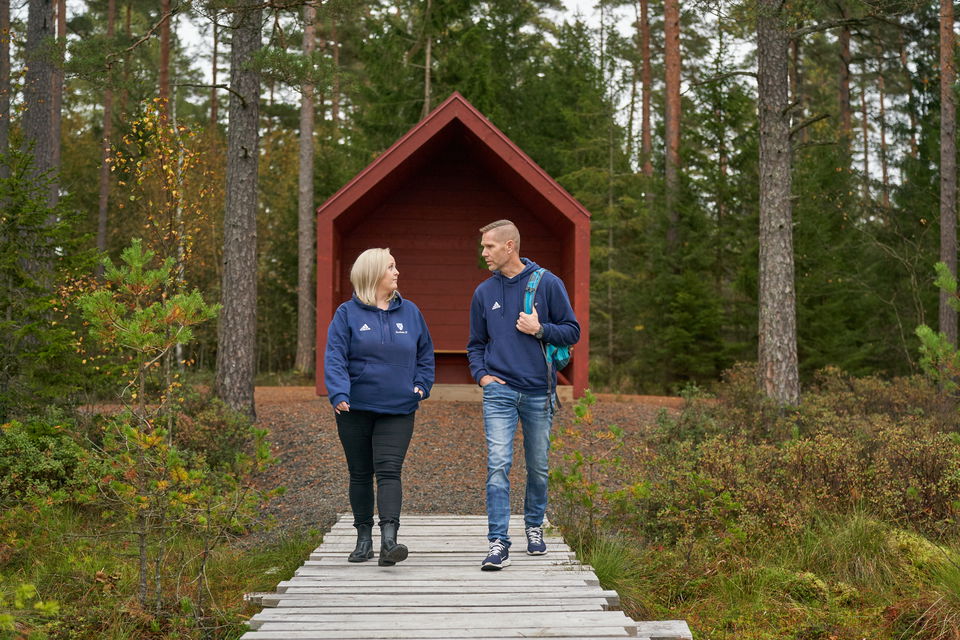 Två personer promenerar från ett vindskydd i skogen