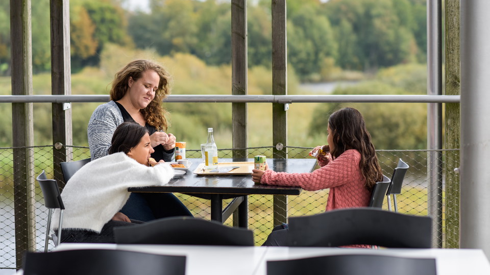 En kvinna och två barn sitter vid ett bord på takterrassen.