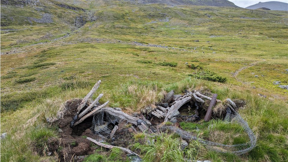 Remains of an old hut, consisting of pieces of wood.