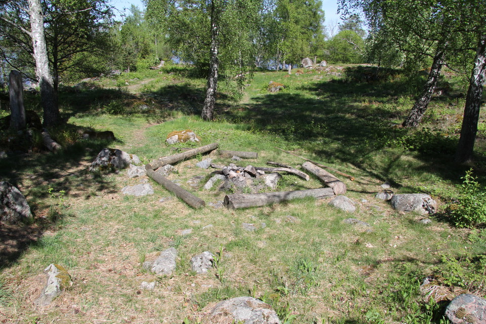 Eldstad och stockar som ligger på marken som bänkar.