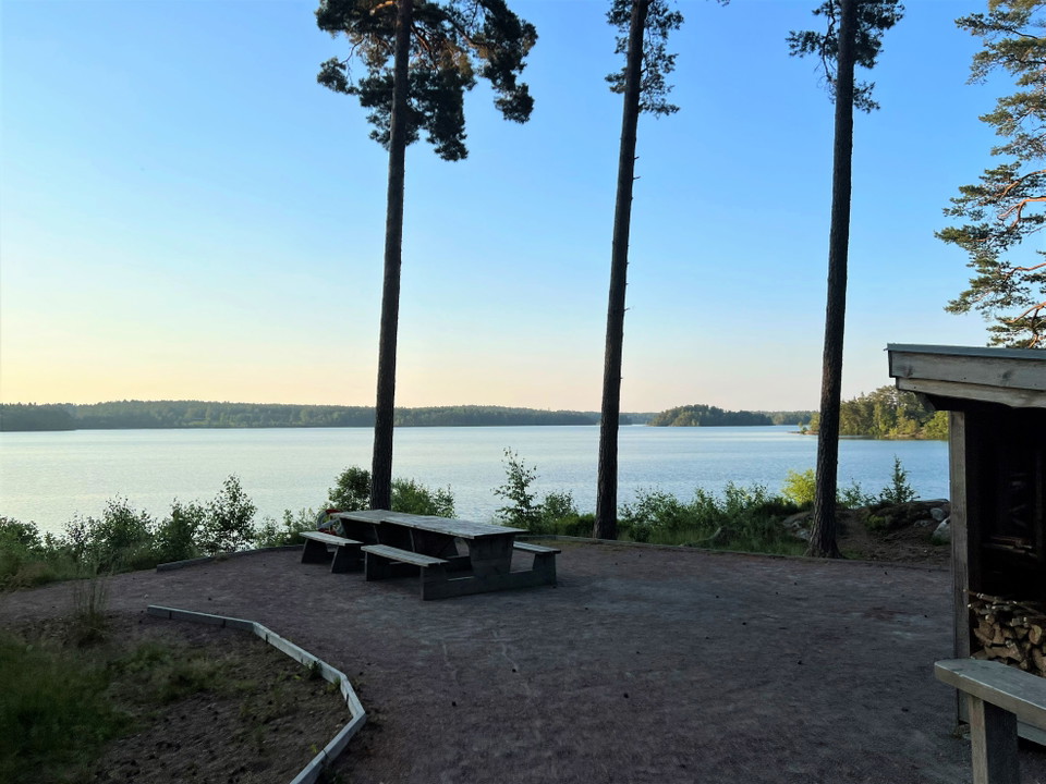 Två picknickbord på en grusad plats med utsikt mot sjön