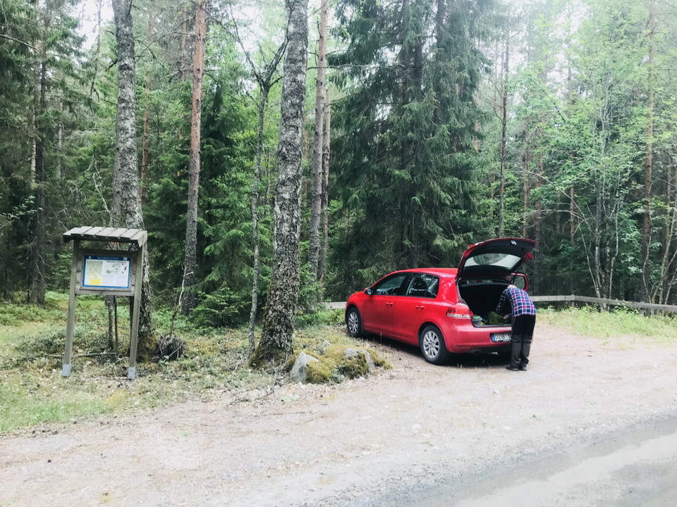 Bild på parkeringsplats, på bilden finns det en röd bil som har baggageluckan öppen