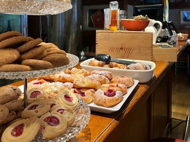 En disk med flera tallrikar med bakverk och vinglas.