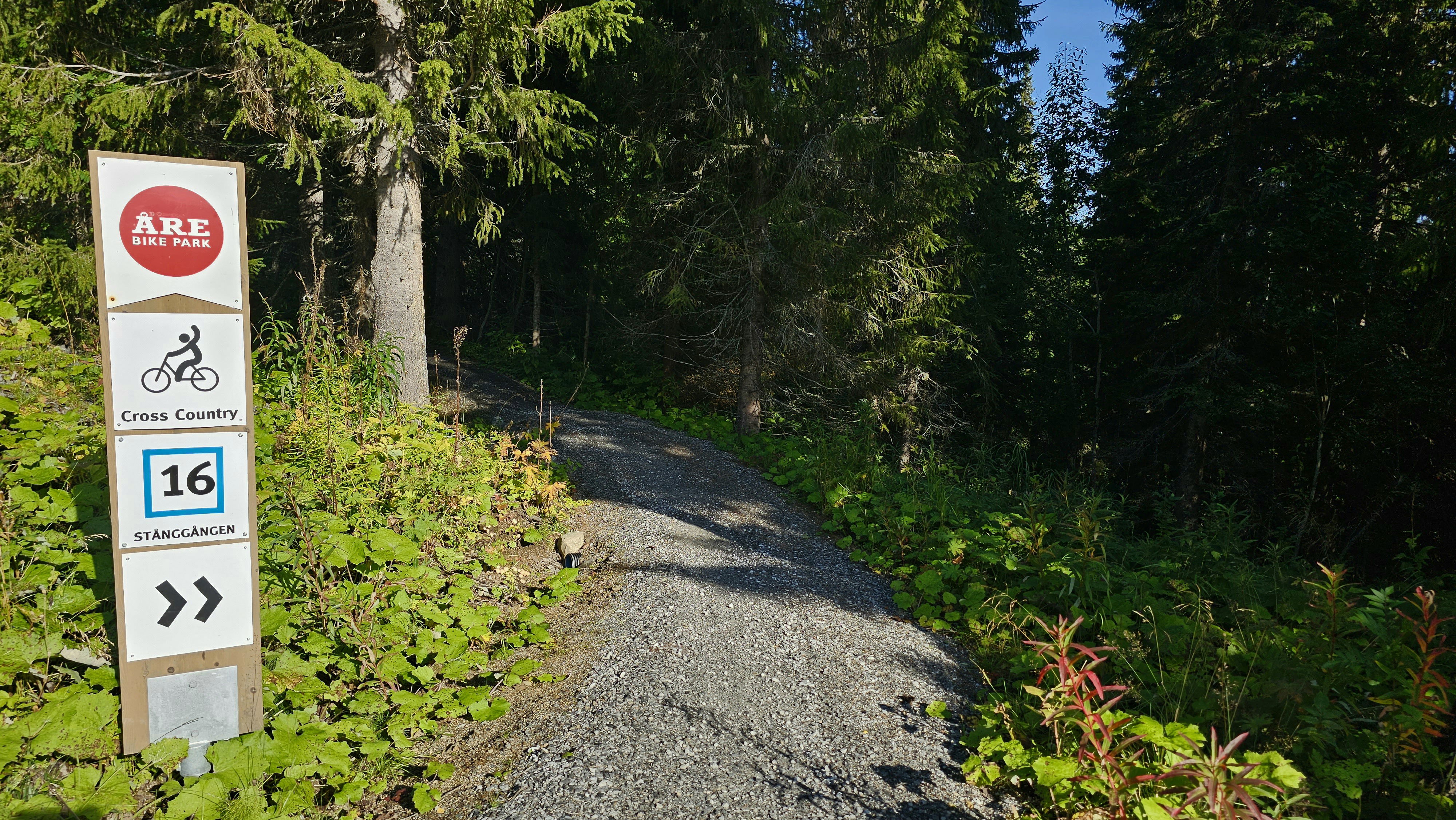 Skylt med nummer 16 Stånggången och en grusad stig som leder in i skogen