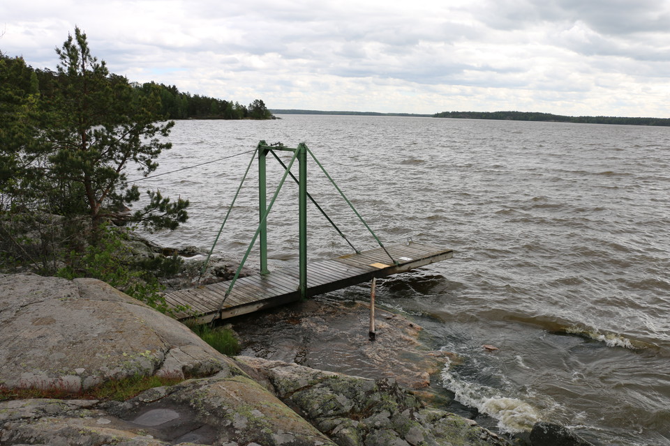 Träbrygga som går ut i vattnet från klippor.
