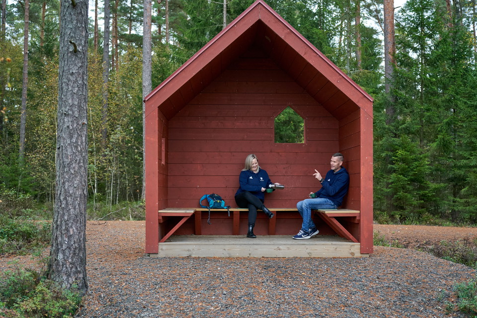 Två personer sitter i ett vindskydd