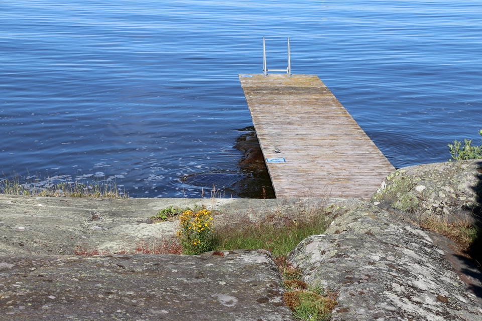 Badplats vid klippor och brygga.