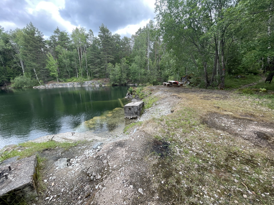 Picknickbord med bänkar och utsikt över ett gammalt stenbrott. På bordet ligger en rod bikini.