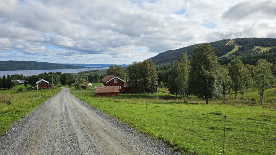 En grusväg med hus på sidorna och en milsvid utsikt över en sjö i bakgrunden.