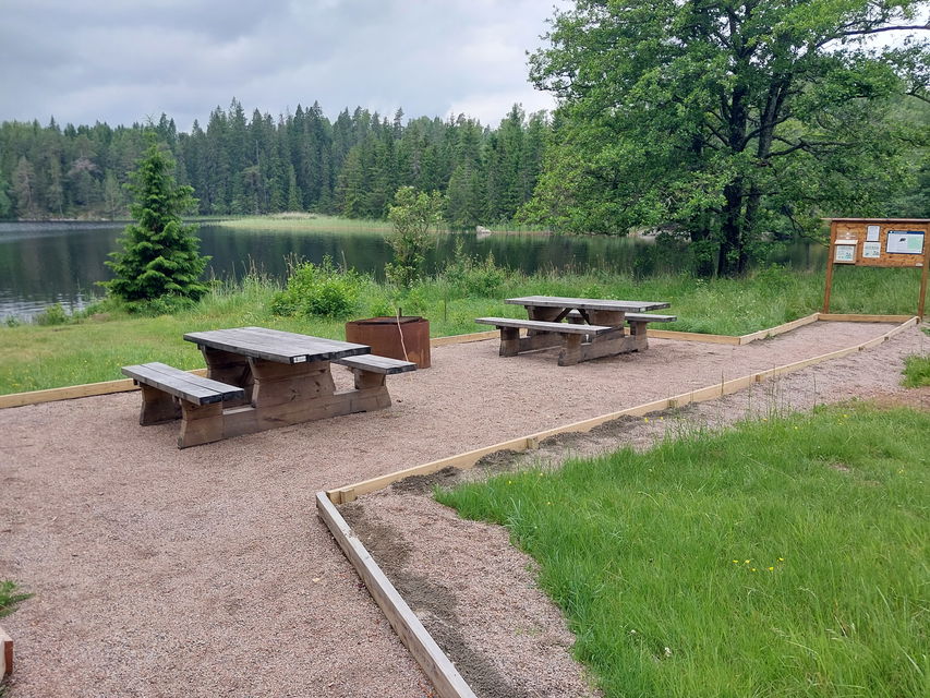 Bänkbord vid grillplatsen med utsikt över sjön.