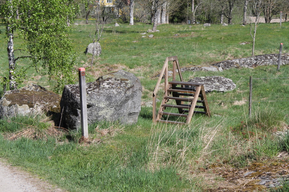 En stätta, en enklare trapp, över staket in i hagen. Stolpe med orange markering visar rätt väg.