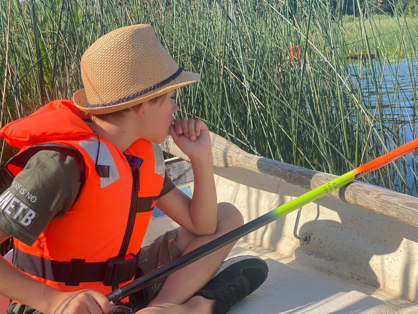 a child sitting in a boat, fishing