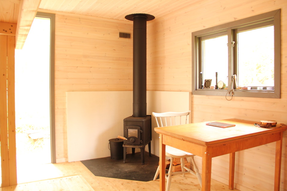 Inne i stugan: kamin, stol och bord