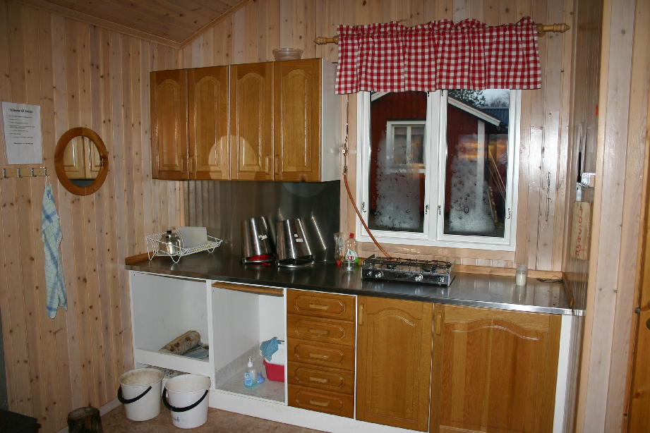 Köksskåp längs en väg med en diskbänk och en gasolspis.
