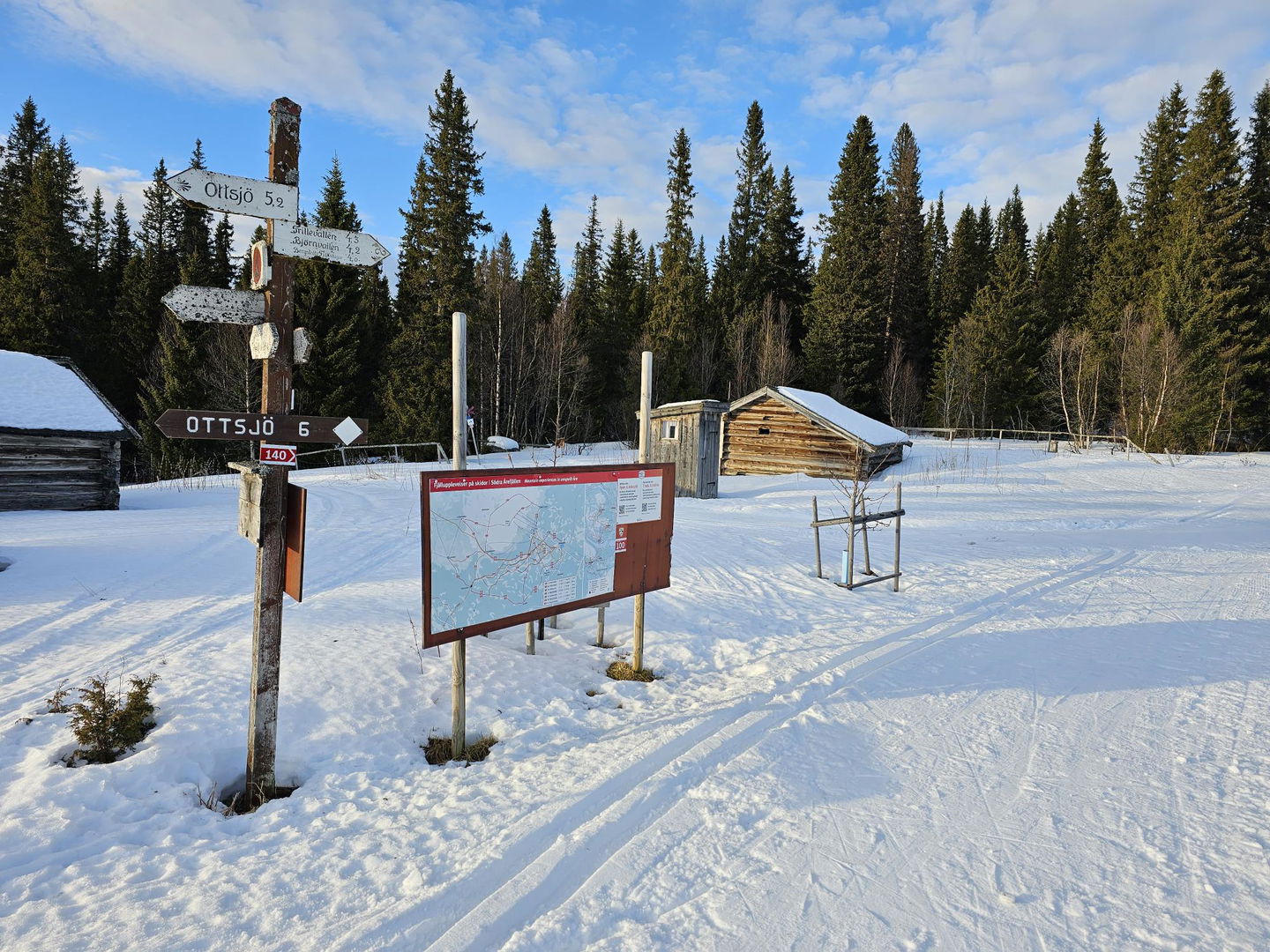 Skyltar och spårkarta bredvid ett skidspår