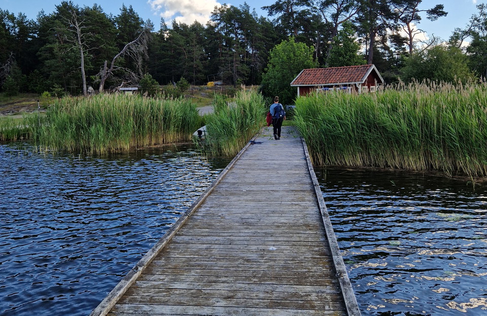 Lång träbrygga. En person går in åt land.