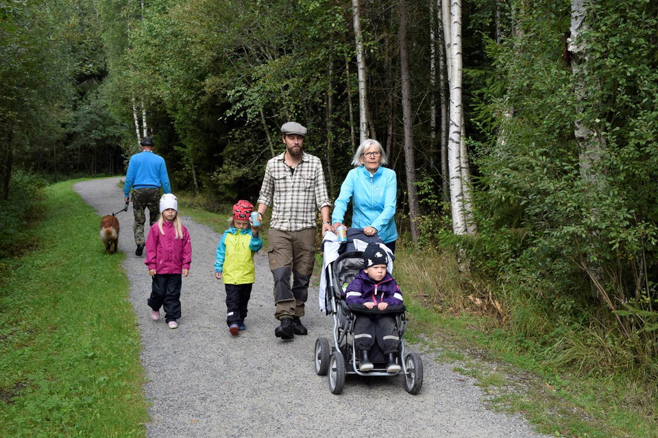 En familj med barn i barnvagn går längs stigen