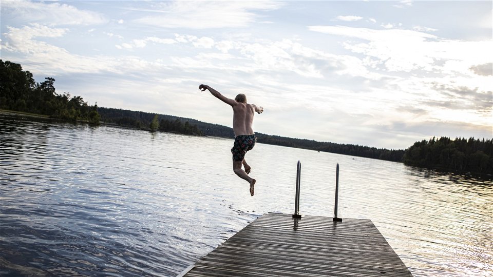 En man hoppar i vattnet från en brygga